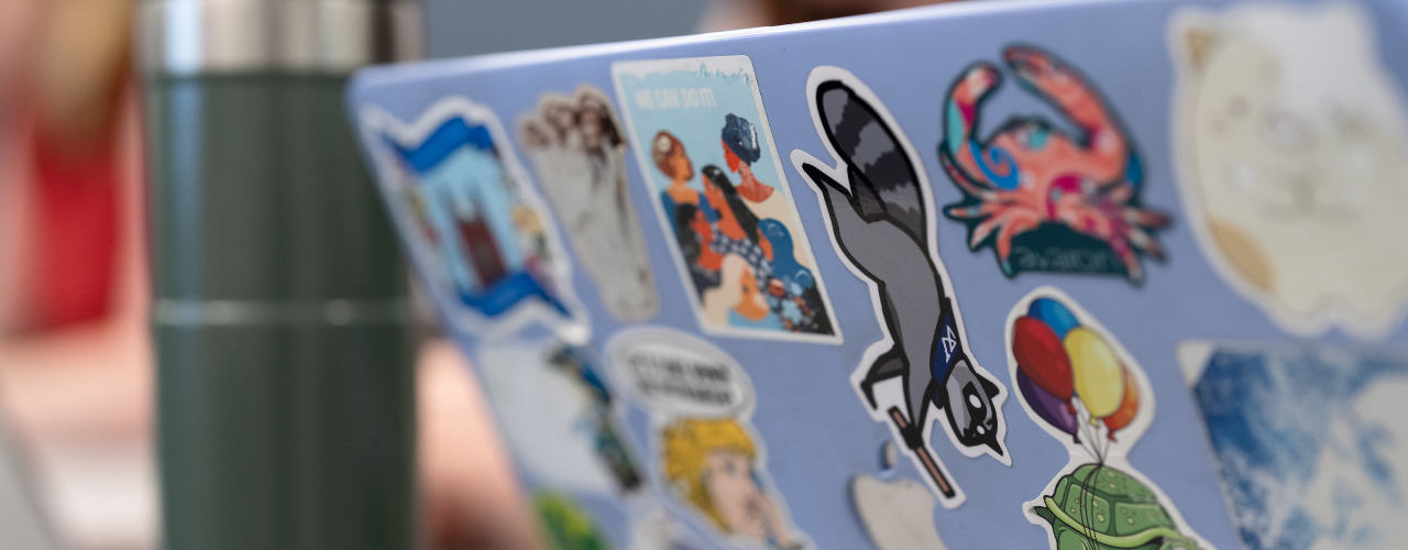 A Wellesley student's laptop with many stickers; focused on a raccoon sticker.